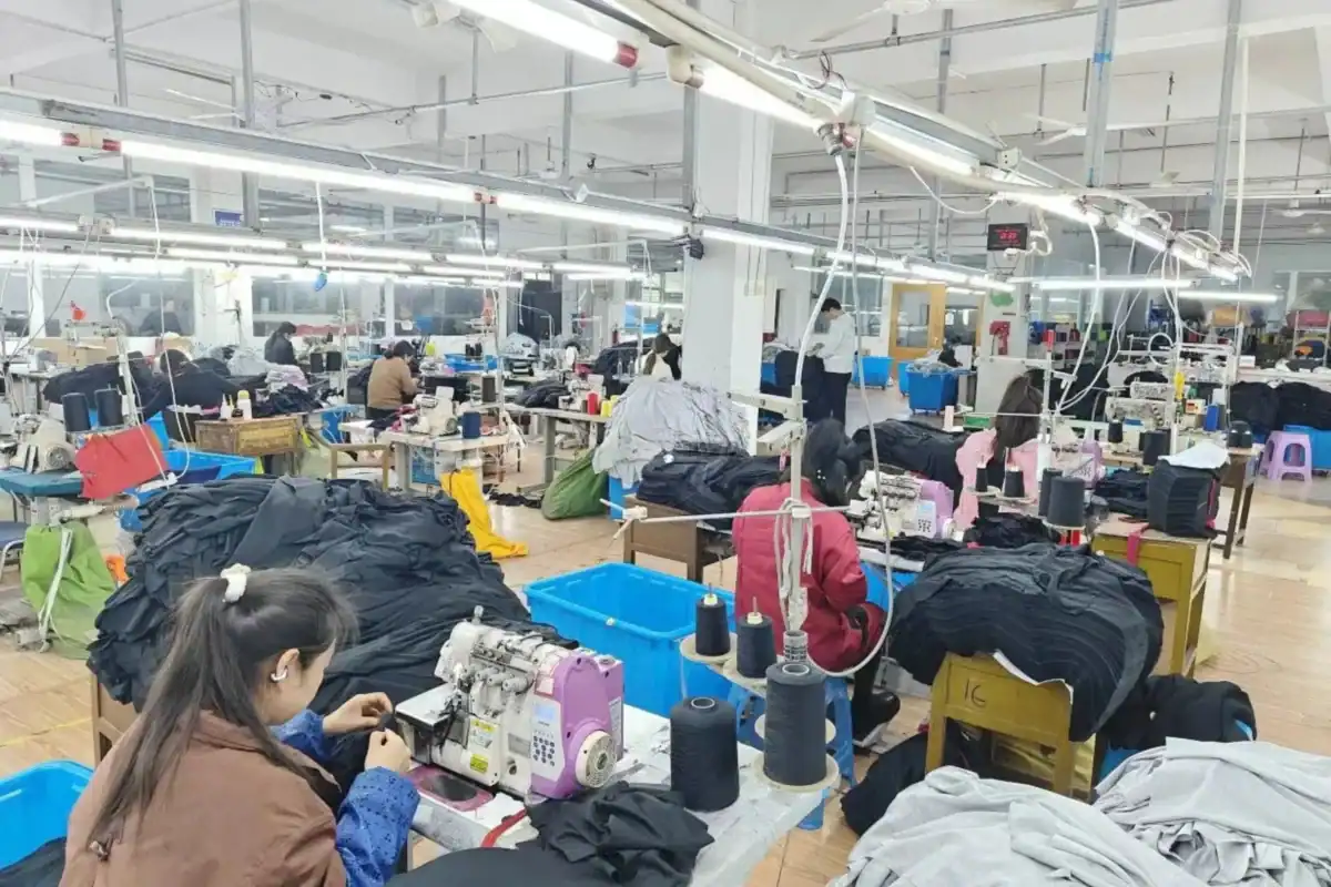 Factory worker stitching a two-tone varsity jacket body and sleeve