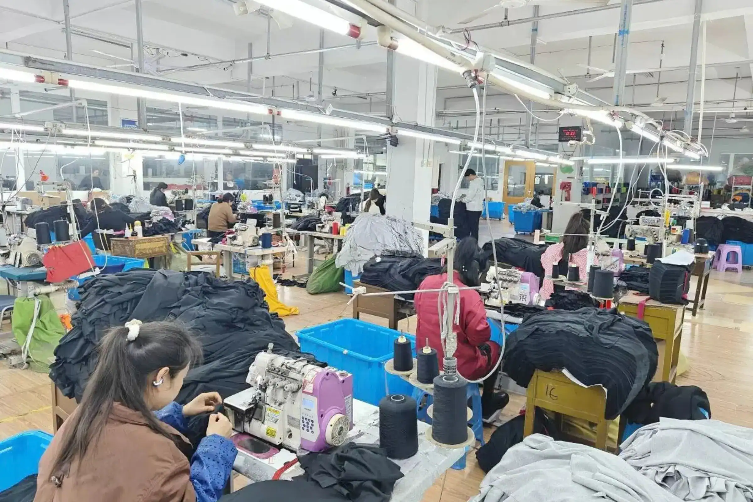 Factory worker stitching a two-tone varsity jacket body and sleeve